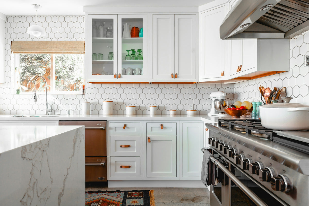 Bright kitchen with white cabinets, hexagonal wall tiles and a marble island