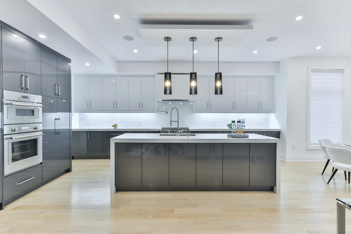Kitchen with grey cabinets, a white island and three pendant lights