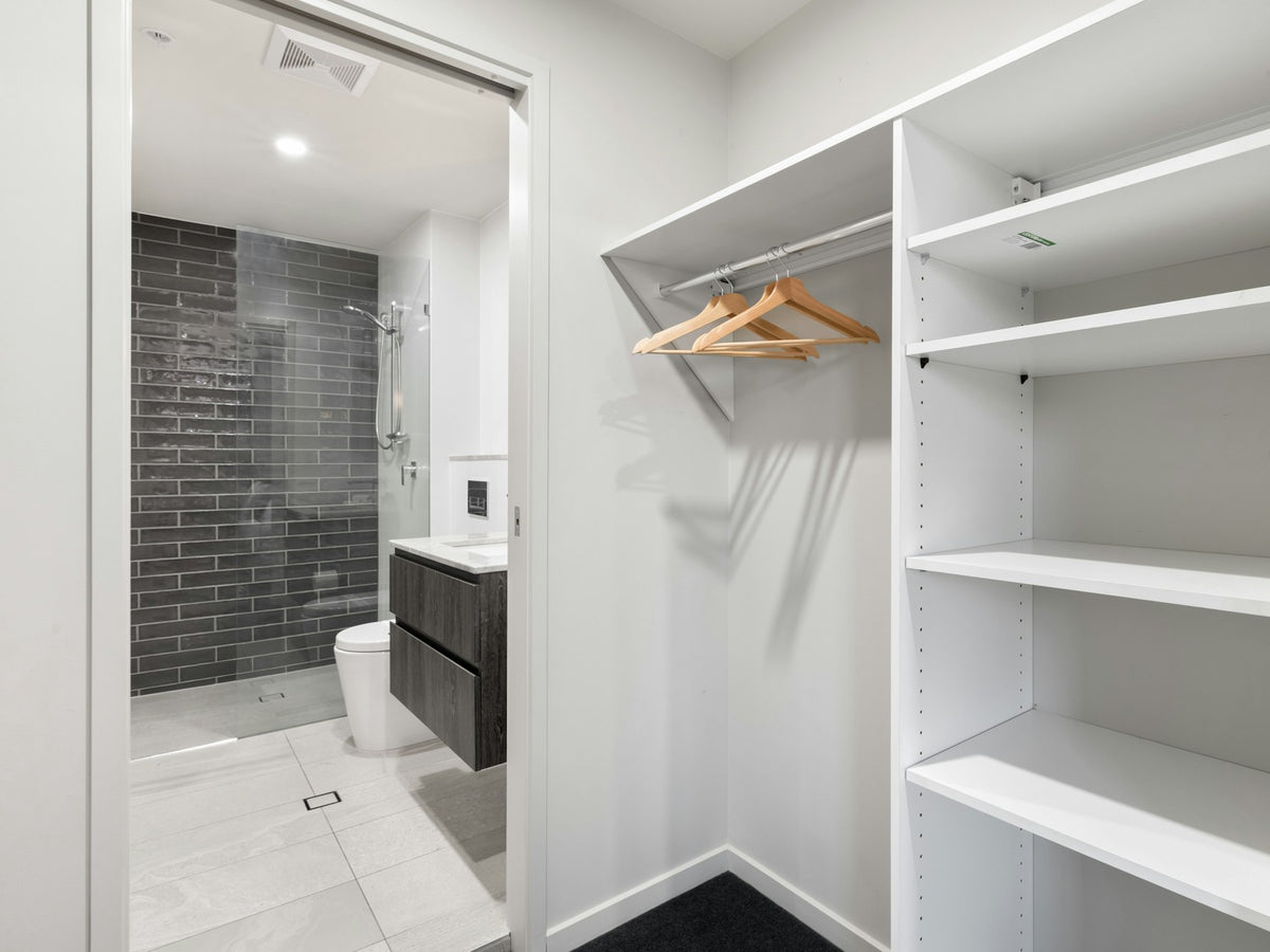Walk-in closet with white shelving and a full-length mirror