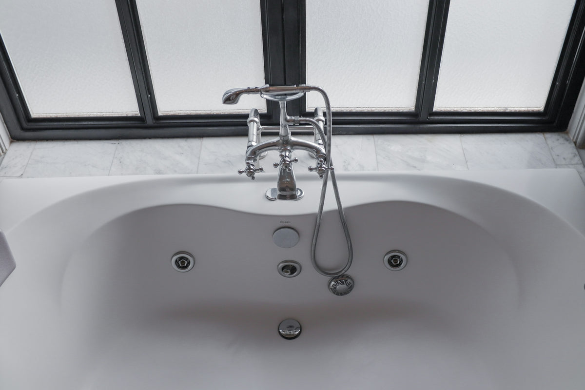 White soaking tub beside a window