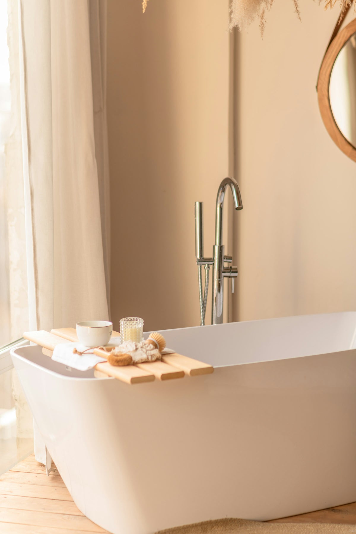 Freestanding white tub beside a window