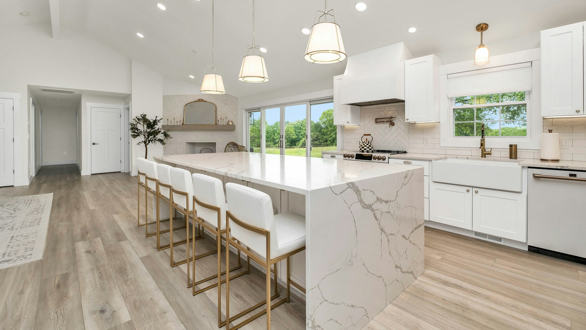 Elegant white kitchen with a marble waterfall island and brass accents