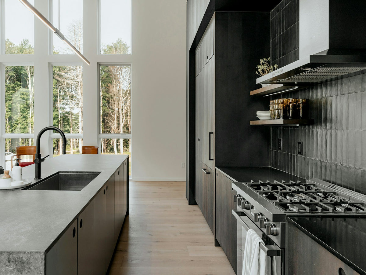Black kitchen cabinetry with a range beside a window