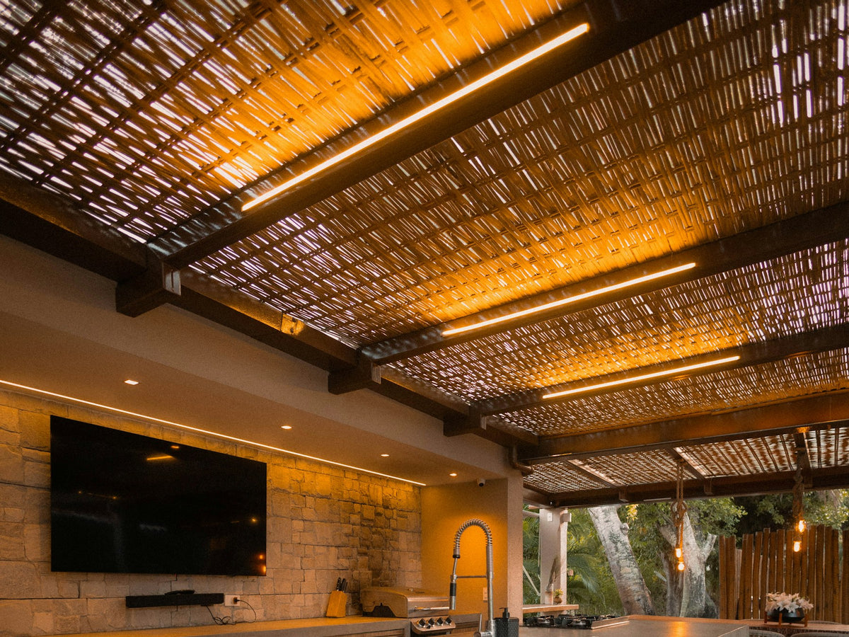 Outdoor kitchen with a stone bar and seating under a pergola