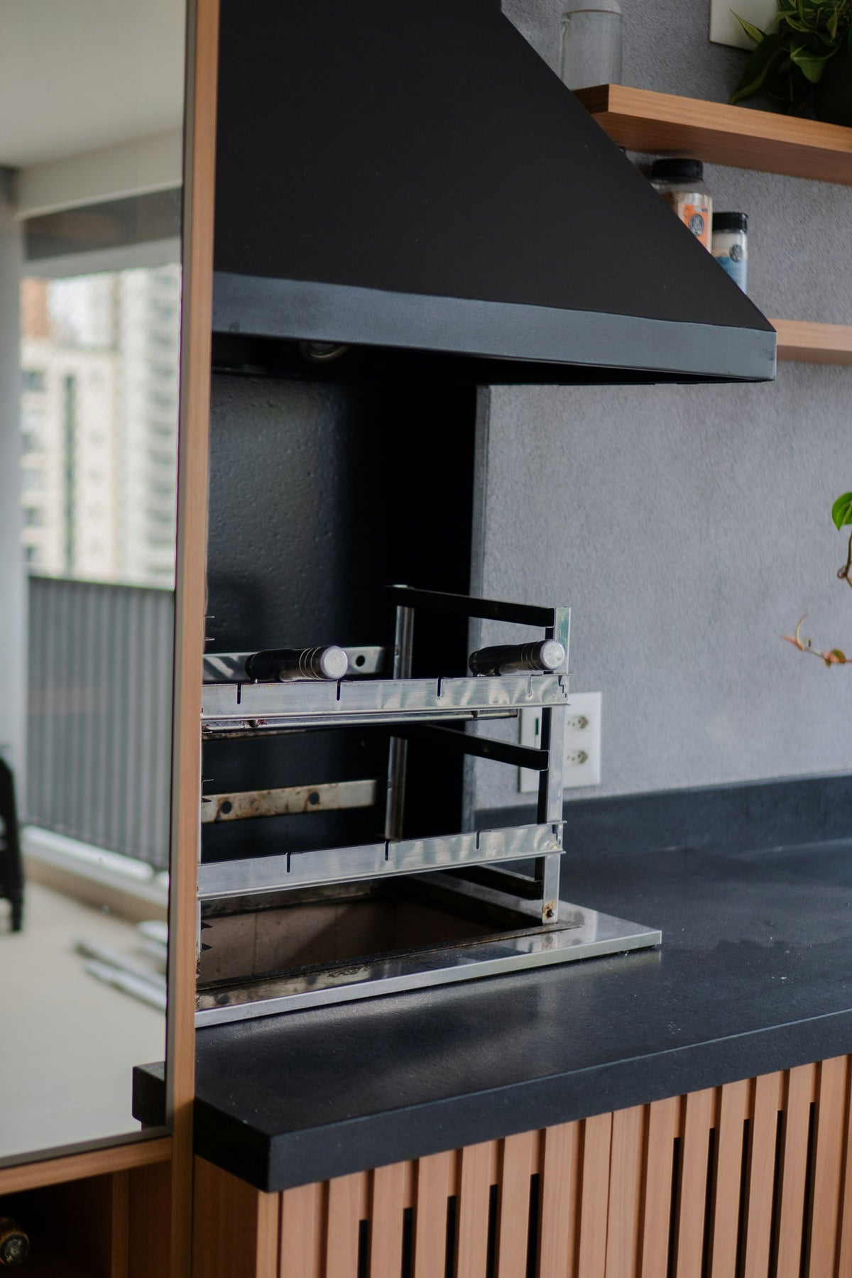 Built-in grill with a black hood and wood cabinet base