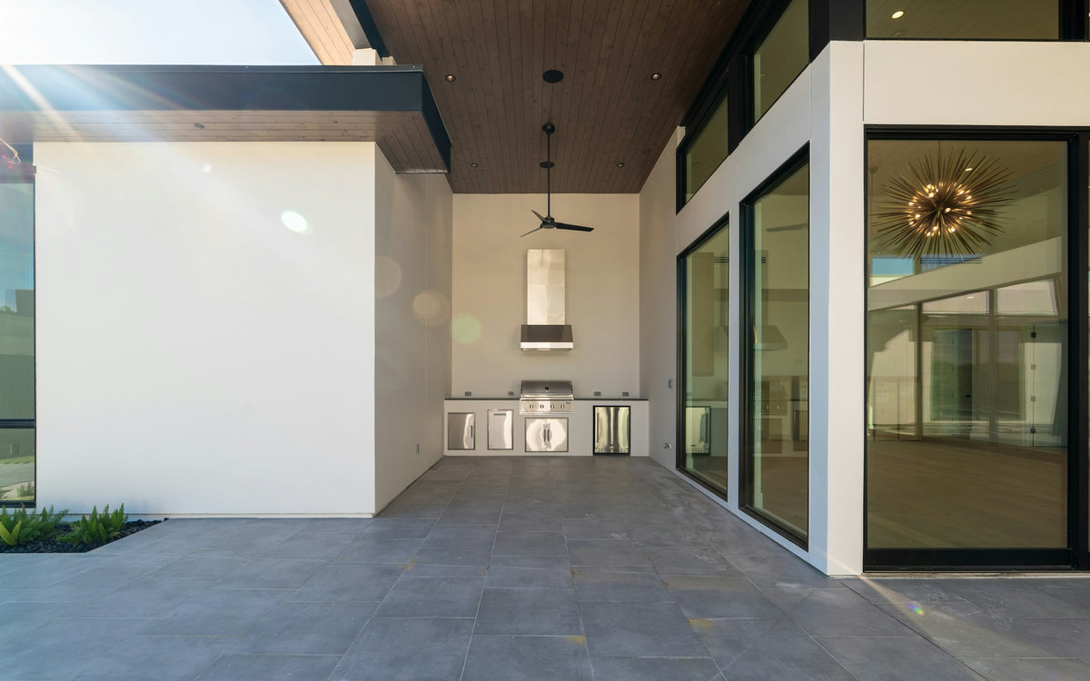 Outdoor kitchen with grill, sink and refrigerator on a covered patio